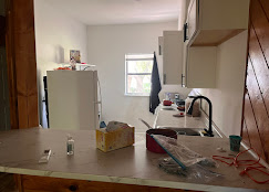 Two workers carefully moving a large washing machine during appliance removal