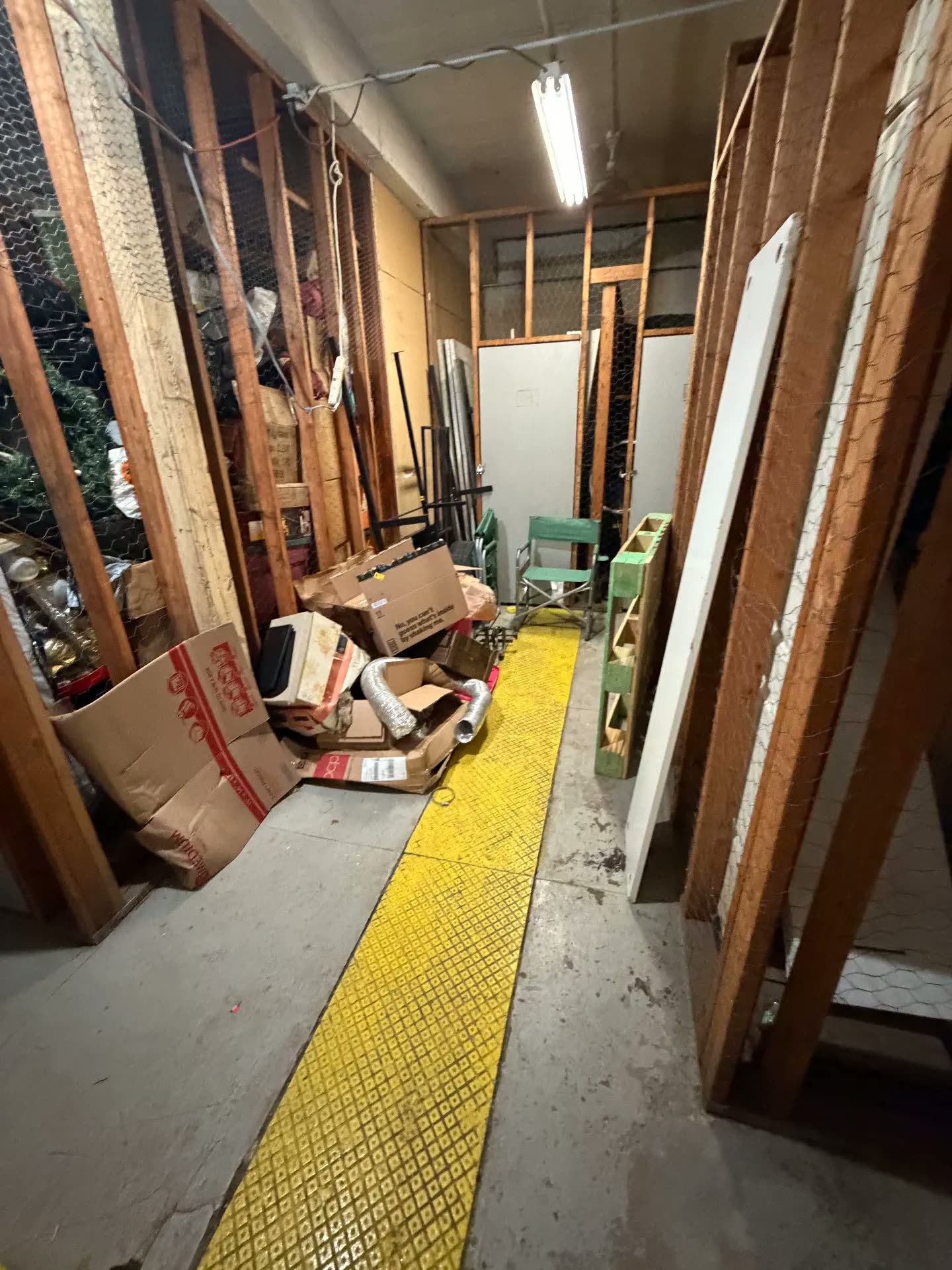 Cluttered basement walkway with boxes and debris