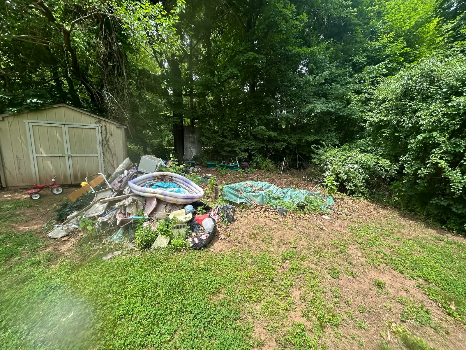Backyard with pool liner and outdoor junk before cleanup