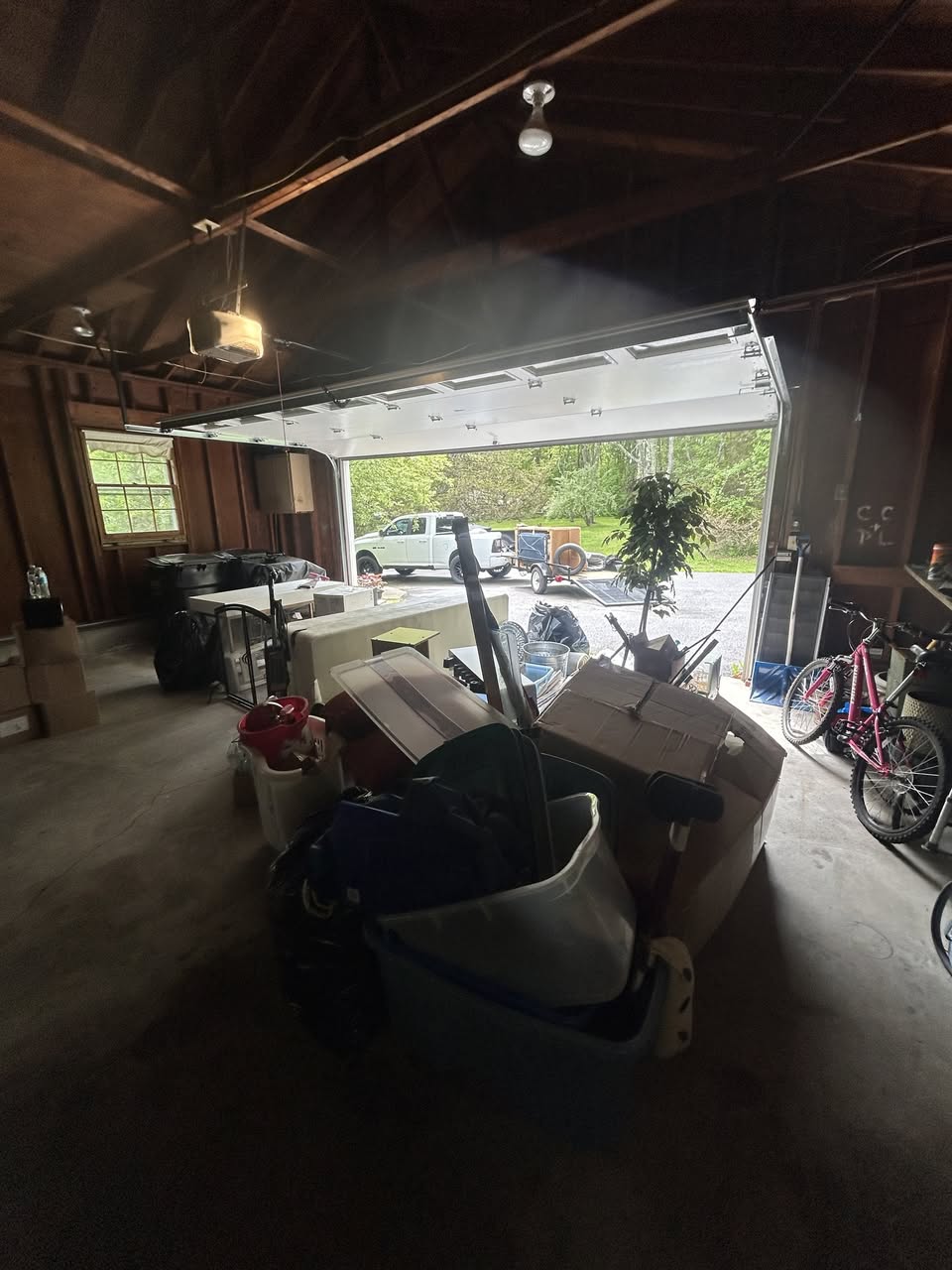 Packed garage before cleanout — truck and trailer parked outside ready to load
